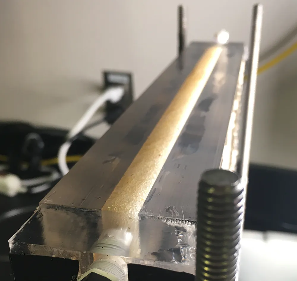 The top edge of a freshly packed sand column filled with water and awaiting an injection of gas. close up of sand layer